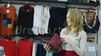 一个有魅力的年轻女人在服装店里选择温暖的冬鞋。 微笑：看着红色的靴子